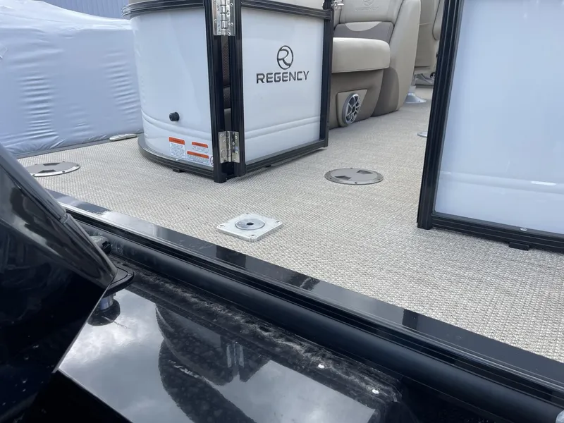 Slide: The Image of 2024 Regency 230 DL3 pontoon boat interior with beige seating and carpeted floor. - 4