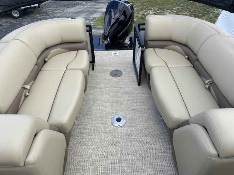 Slide: The Image of 2024 Regency 230 DL3 pontoon boat with beige seating and outboard motor. - 7