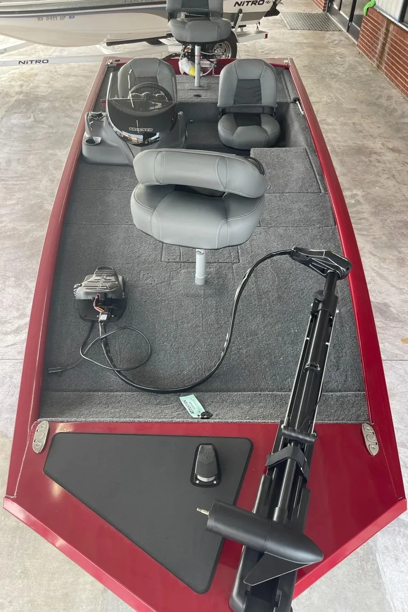 Slide: The Image of 2024 Tracker Pro 170 fishing boat with gray seats and red exterior. - 2
