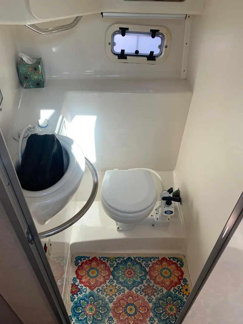 Slide: The Image of 1998 Maxum 2800 SCR boat bathroom with toilet, sink, and colorful mat. - 29