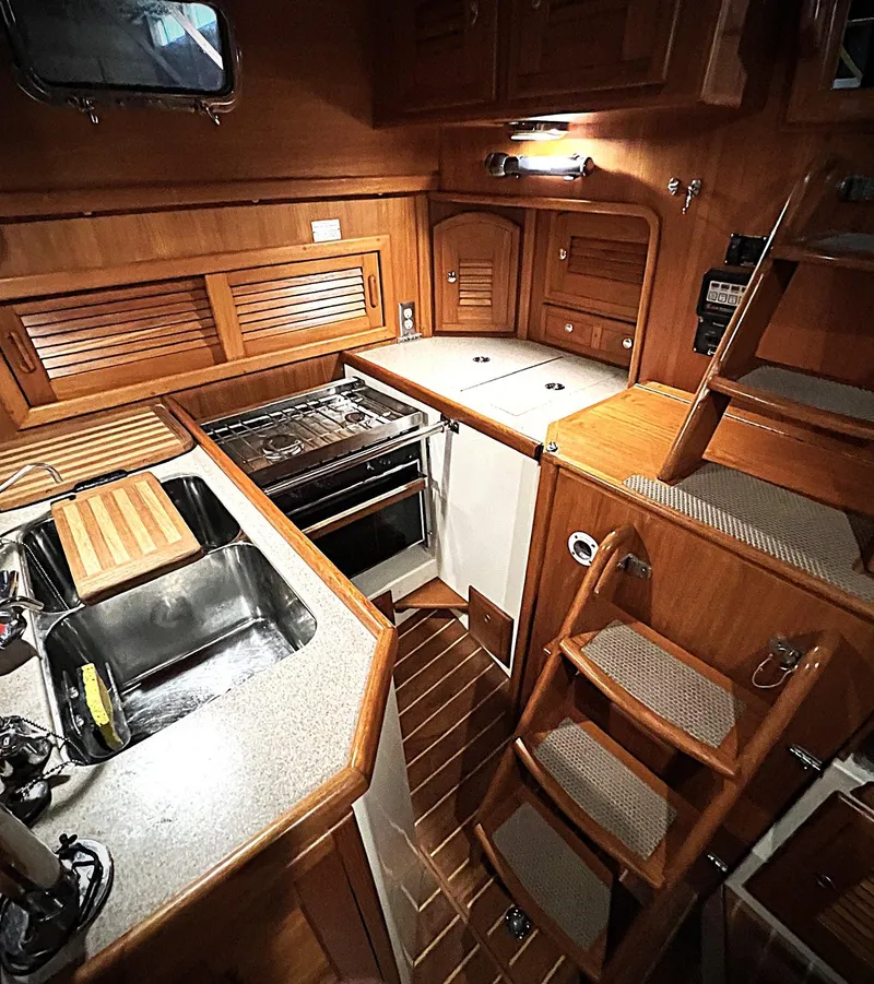 Slide: The Image of Cozy 2000 Pacific Seacraft 37 yacht interior with wooden cabinetry and compact kitchen. - 5