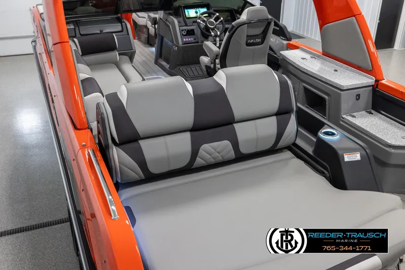 Slide: The Image of 2024 Avalon Excalibur VRB boat interior with gray and black seating, orange exterior, and Reeder-Trausch Marine logo. - 11