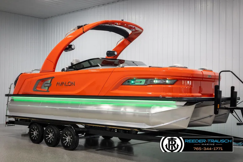 Slide: The Image of 2024 Avalon Excalibur VRB pontoon boat in vibrant orange on a trailer. - 2