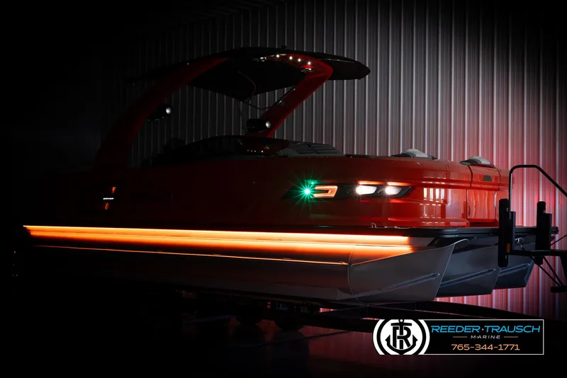Slide: The Image of 2024 Avalon Excalibur VRB pontoon boat with LED lights in a dimly lit showroom. - 4