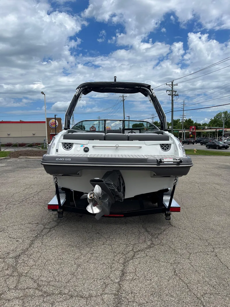 Slide: The Image of 2025 Crownline 240 SS boat, rear view, parked on pavement under a cloudy sky. - 12
