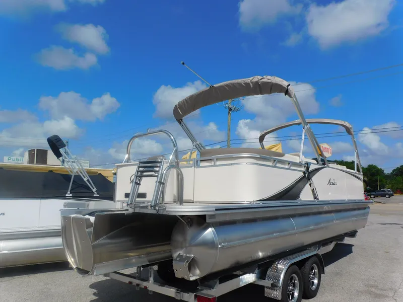 Slide: The Image of 2024 Avalon LSZ Quad Lounger pontoon boat on trailer under blue sky. - 5
