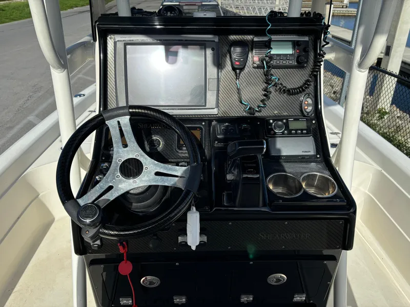 Slide: The Image of 2014 ShearWater 25LTZ boat console with steering wheel, electronics, and cup holders. - 14