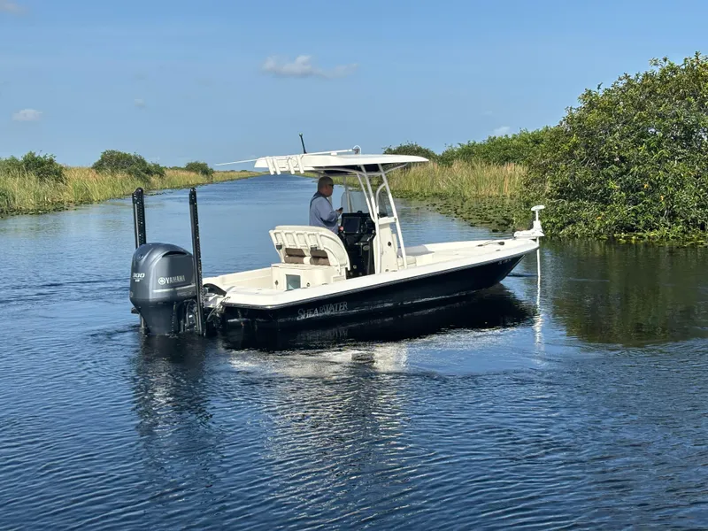 Slide: The Image of 2014 ShearWater 25LTZ boat navigating a calm waterway with lush greenery. - 3