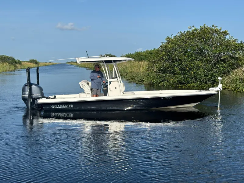 Slide: The Image of 2014 ShearWater 25LTZ boat on calm water with lush greenery. - 4