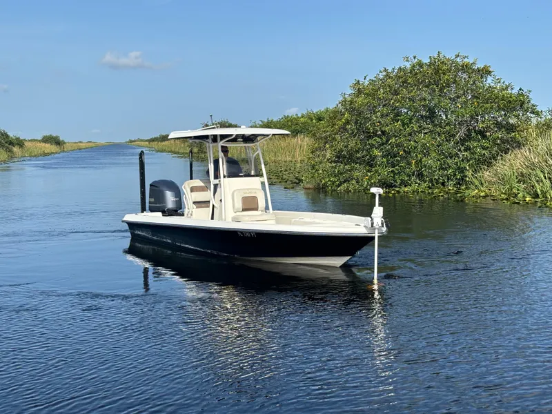 Slide: The Image of 2014 ShearWater 25LTZ boat cruising on a calm waterway, surrounded by lush greenery. - 5
