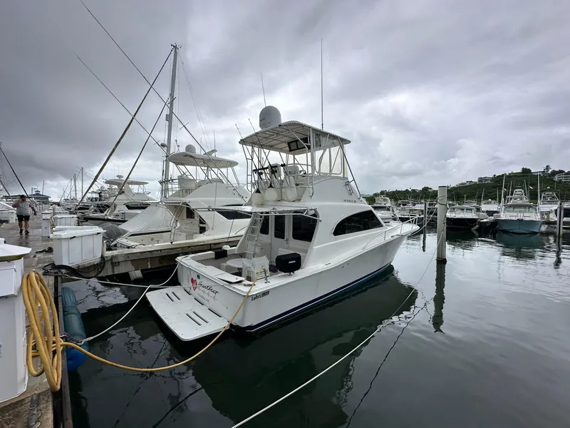 Slide: The Image of 2005 Luhrs 38 Convertible yacht docked at marina under cloudy skies. - 2