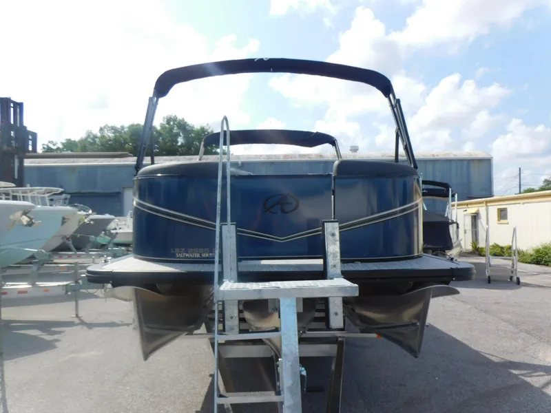 Slide: The Image of 2024 Avalon LSZ Quad Lounger pontoon boat, rear view, on trailer, outdoor setting. - 2