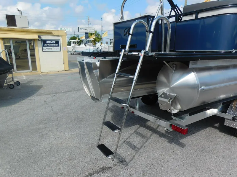 Slide: The Image of 2024 Avalon LSZ Quad Lounger pontoon boat rear view with ladder and service department in background. - 7