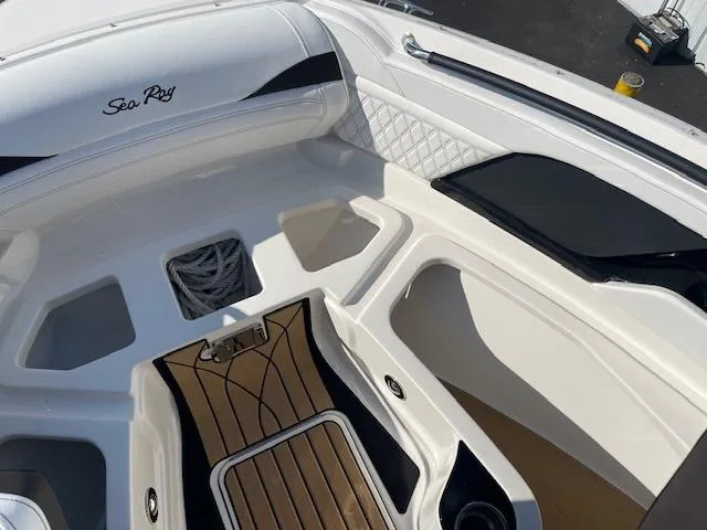 Slide: The Image of 2024 Sea Ray SLX 260 boat interior with white seating and wood flooring. - 6