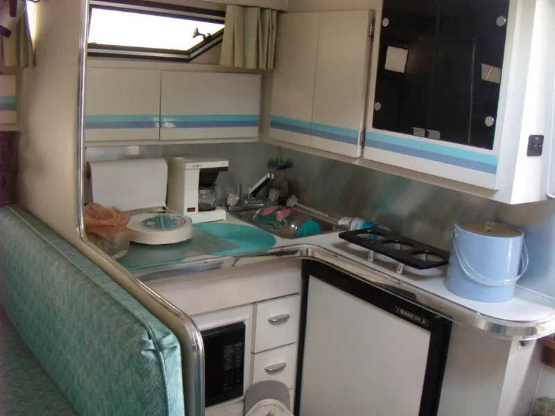 Slide: The Image of 1988 Wellcraft St. Tropez 3200 boat interior kitchen with appliances and seating. - 18