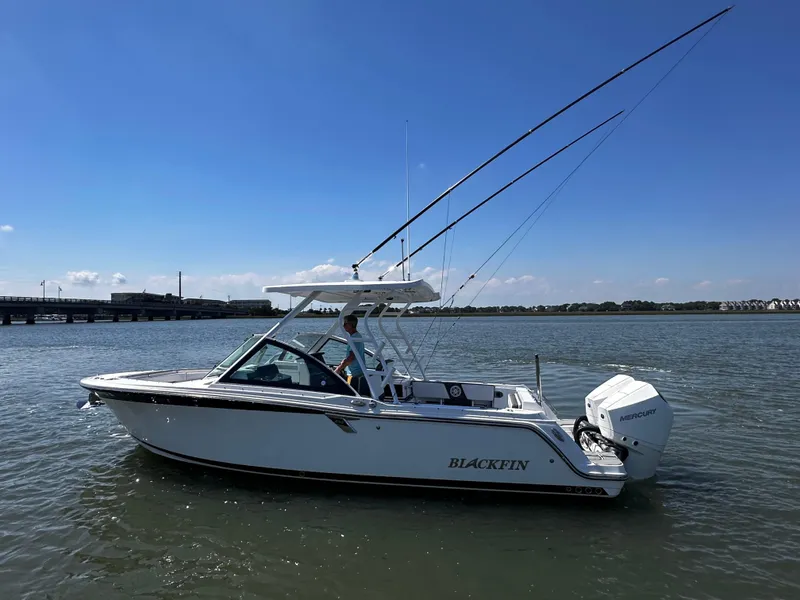 Slide: The Image of 2021 Blackfin 252 DC boat on calm water with fishing rods. - 2