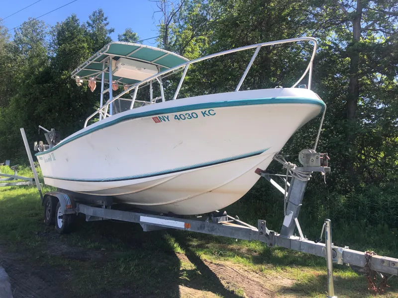 The Image of 1996 Mako 22 Center Console boat on trailer, parked outdoors near trees. - 0