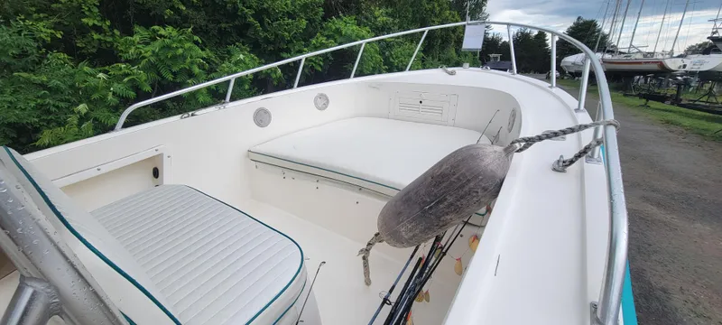 Slide: The Image of 1996 Mako 22 Center Console boat with seating, docked near lush greenery. - 15