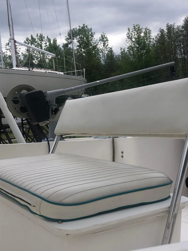 Slide: The Image of 1996 Mako 22 Center Console boat with white seating, docked near trees. - 24