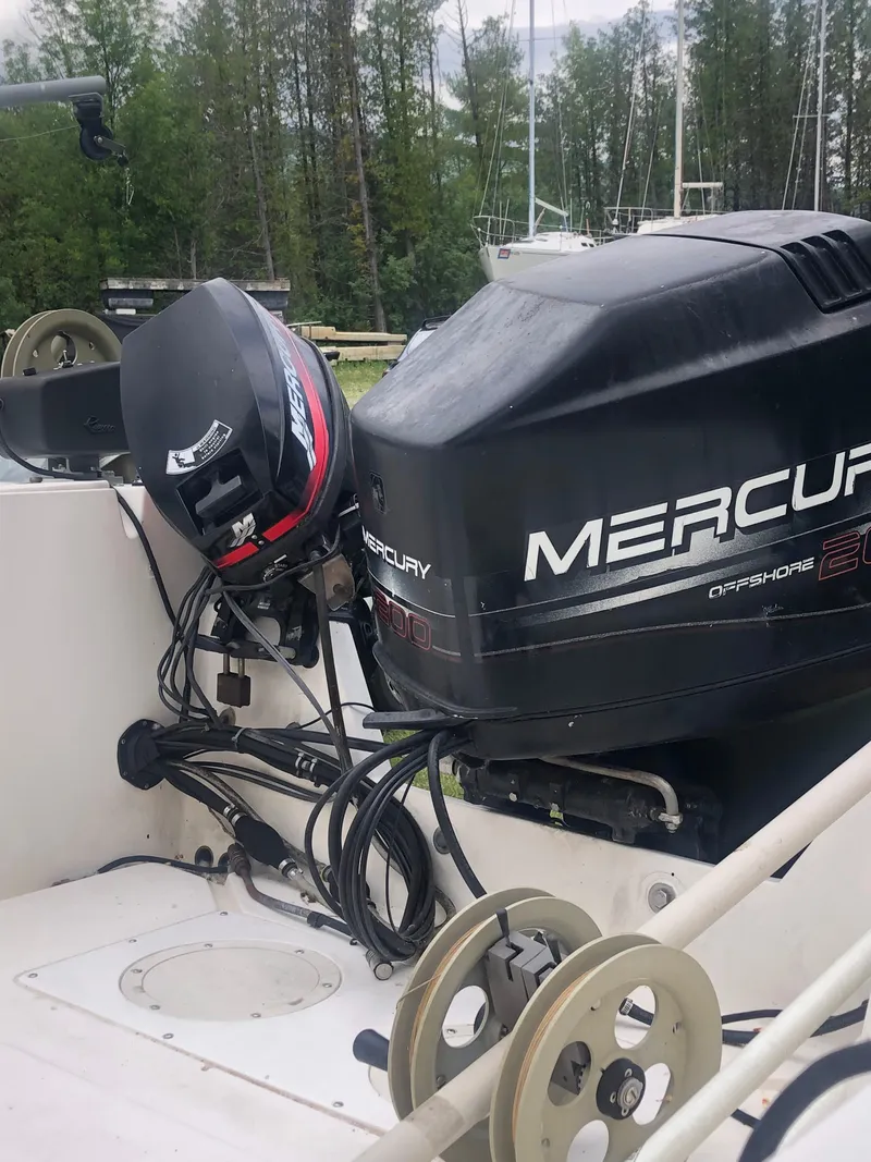 Slide: The Image of 1996 Mako 22 Center Console boat with Mercury outboard motor, docked near trees. - 31