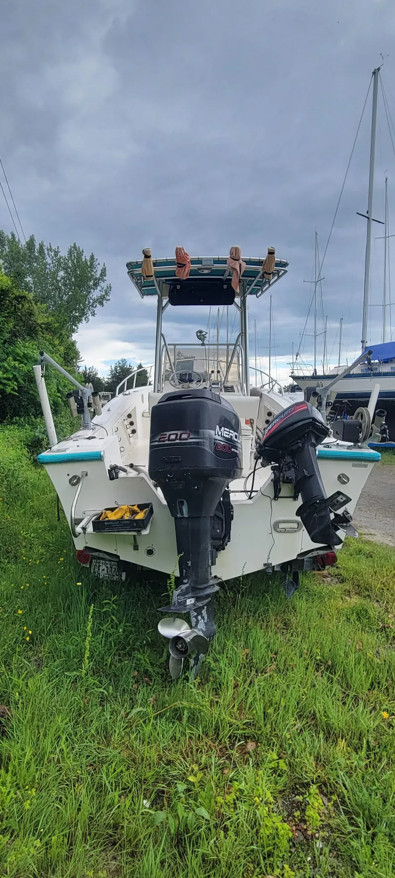 Slide: The Image of 1996 Mako 22 Center Console boat with outboard motor, parked on grass under cloudy sky. - 5