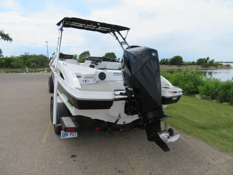 Slide: The Image of 2022 Tahoe 210 S Limited boat with outboard motor on trailer near lake. - 2