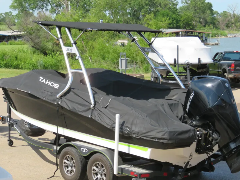 Slide: The Image of 2022 Tahoe 210 S Limited boat with cover on trailer near a lake. - 22