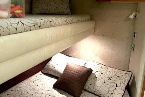 Slide: The Image of Interior cabin of a 1992 Sea Ray Sundancer with bunk beds and floral bedding. - 26