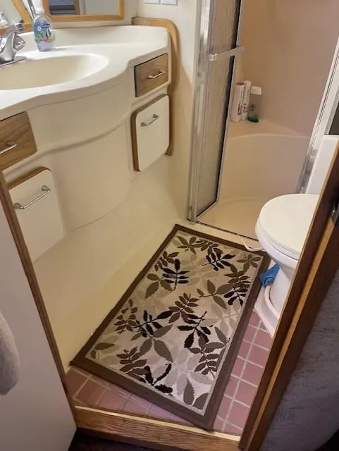 Slide: The Image of 1992 Sea Ray Sundancer bathroom with sink, shower, toilet, and floral rug. - 29