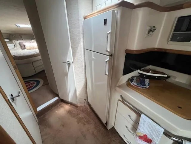 Slide: The Image of 1992 Sea Ray Sundancer interior kitchen area with refrigerator and bedroom view. - 30