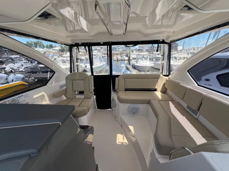 Slide: The Image of Interior of 2017 Pursuit OS 355 Offshore boat with beige seating and marina view. - 15