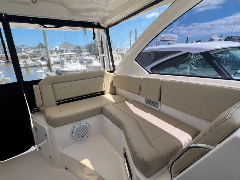 Slide: The Image of 2017 Pursuit OS 355 Offshore boat interior with beige seating at marina. - 16