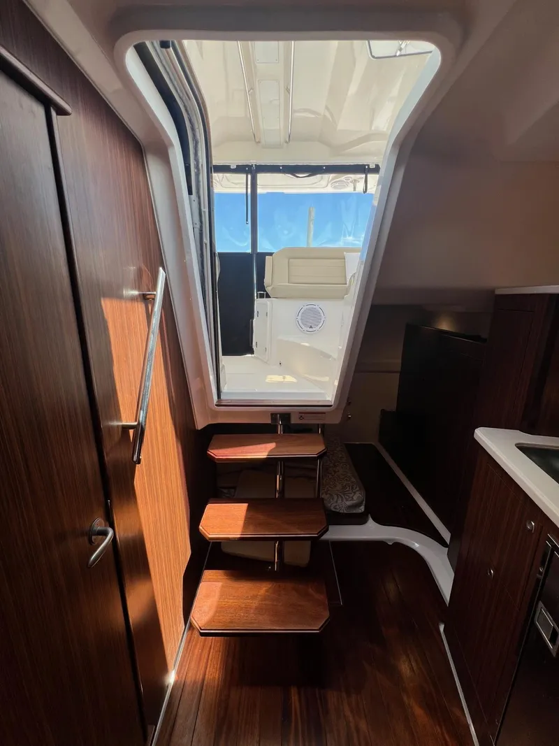 Slide: The Image of Interior view of 2017 Pursuit OS 355 Offshore boat with wooden steps and modern design. - 23