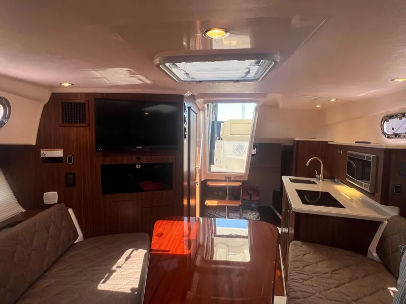 Slide: The Image of Interior of 2017 Pursuit OS 355 Offshore boat with seating, table, TV, and kitchenette. - 24