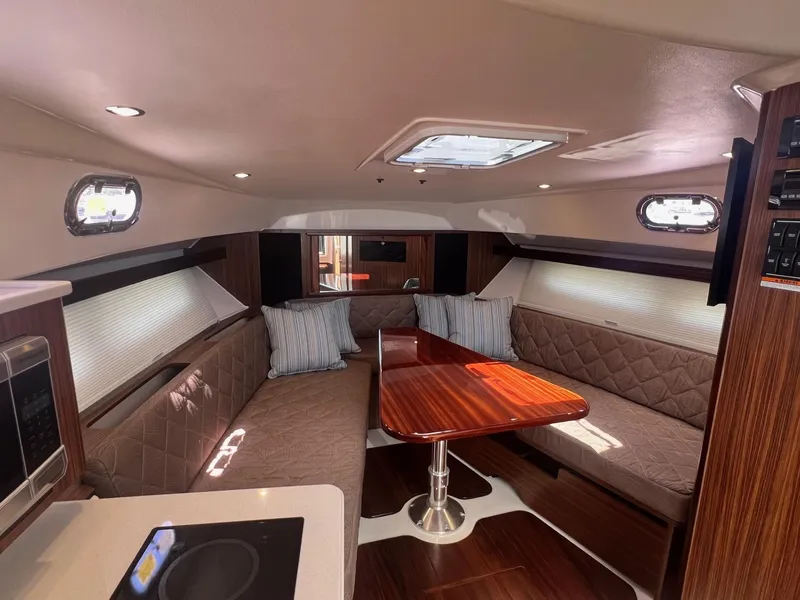 Slide: The Image of 2017 Pursuit OS 355 Offshore cabin interior with dining area and plush seating. - 25