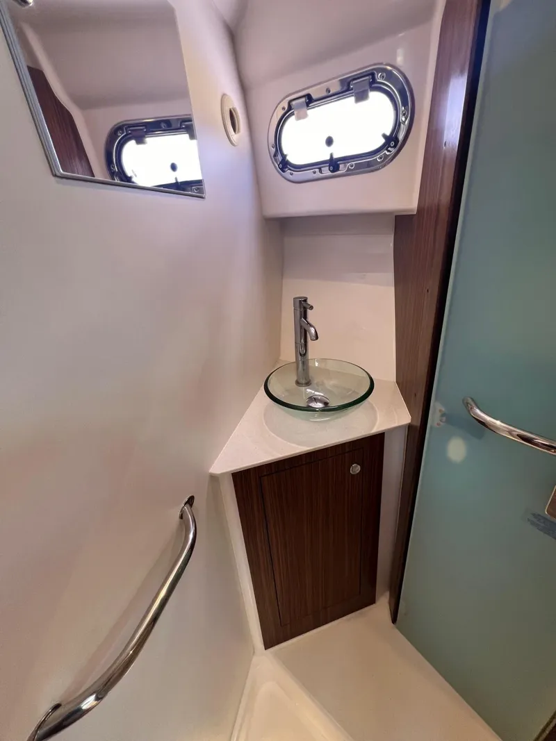 Slide: The Image of Compact bathroom in 2017 Pursuit OS 355 Offshore boat with modern sink and porthole window. - 31