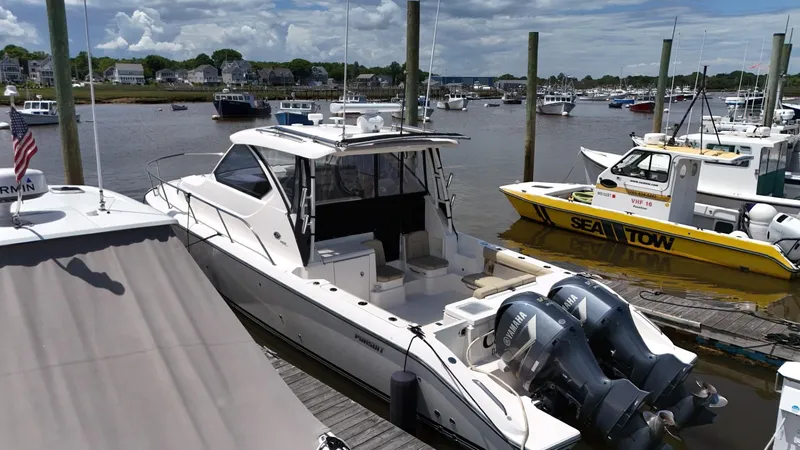 Slide: The Image of 2017 Pursuit OS 355 Offshore boat docked at a marina with twin outboard engines. - 7