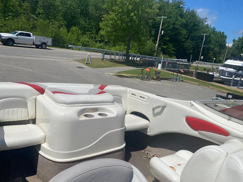 Slide: The Image of 2005 Stingray 195 LS/LX boat interior with white and red seating, parked near a marina. - 5