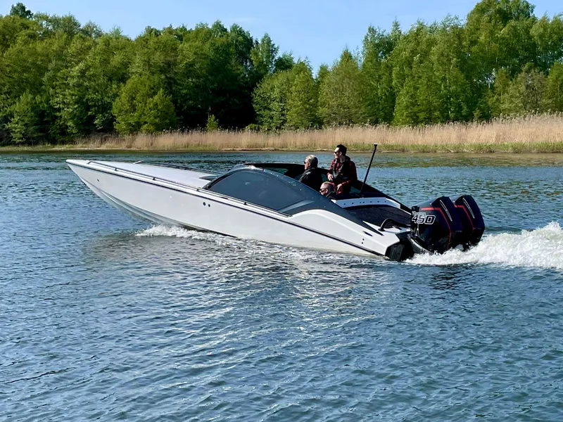 Slide: The Image of 2022 Nitra Boats 30 SkyTop cruising on a lake with lush green trees in the background. - 2