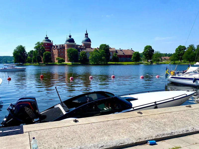 Slide: The Image of 2022 Nitra Boats 30 SkyTop docked by a scenic castle and lake. - 5