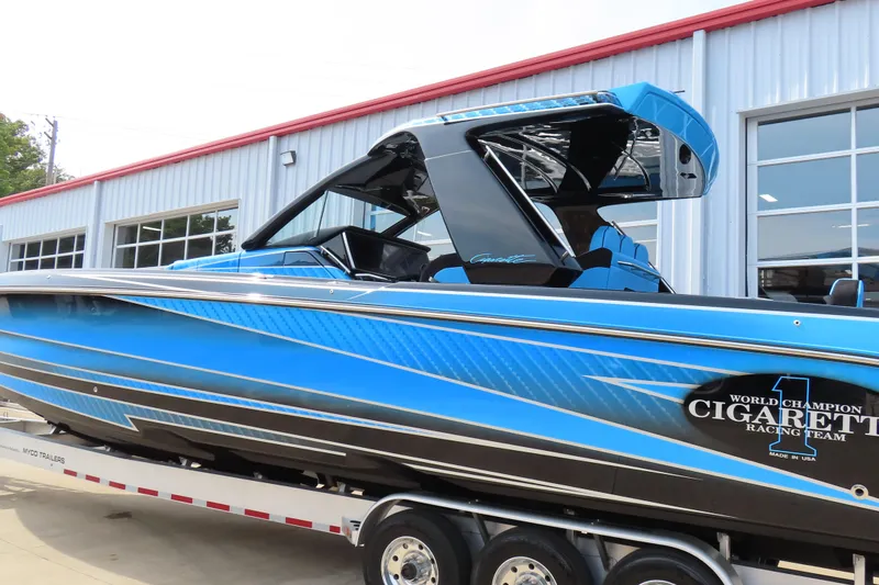 Slide: The Image of 2025 Cigarette 41 Nighthawk boat in blue, displayed on a trailer outside a building. - 3