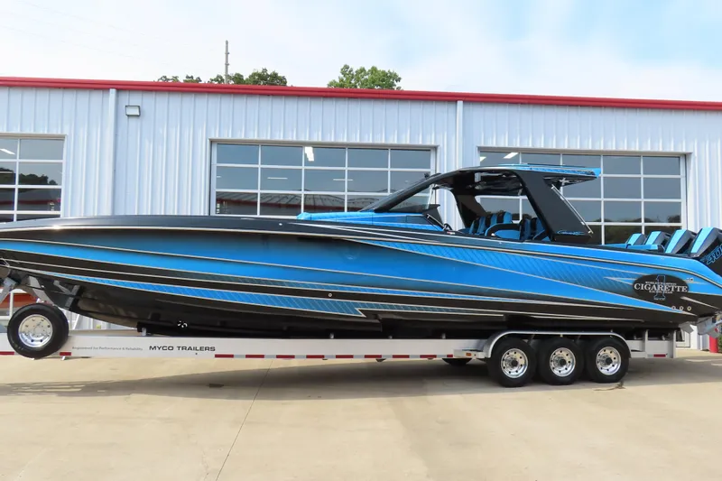 Slide: The Image of 2025 Cigarette 41 Nighthawk boat in blue, on a trailer outside a garage. - 45