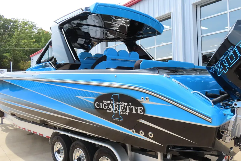 Slide: The Image of 2025 Cigarette 41 Nighthawk boat in blue, displayed on a trailer outside a building. - 65