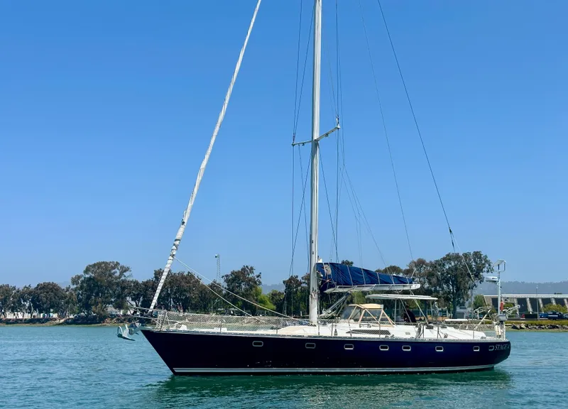 Slide: The Image of 1983 Tayana 55 sailboat on calm water under clear blue sky. - 1