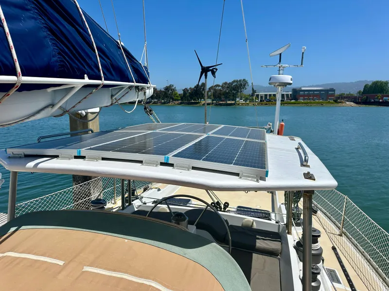Slide: The Image of Sailboat with solar panels on deck, Tayana 55, 1983 model, docked by a scenic waterfront. - 11