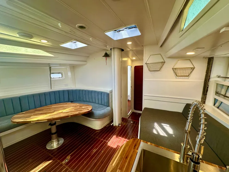 Slide: The Image of Interior of 1983 Tayana 55 yacht with modern seating, wooden table, and sleek kitchen area. - 16