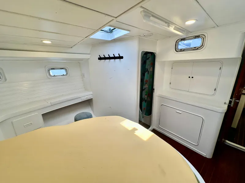 Slide: The Image of Interior of 1983 Tayana 55 yacht, featuring white walls, windows, and a skylight. - 31