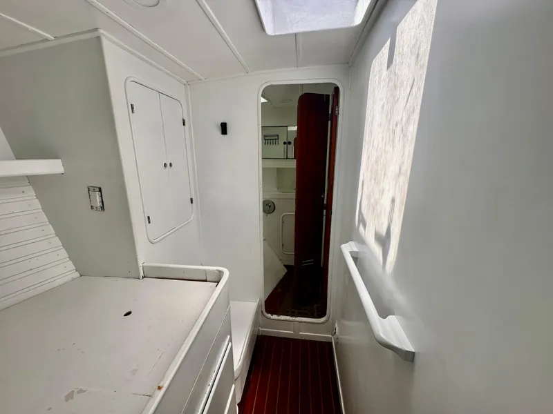 Slide: The Image of Interior of 1983 Tayana 55 yacht, featuring white walls, wooden floor, and natural light. - 34