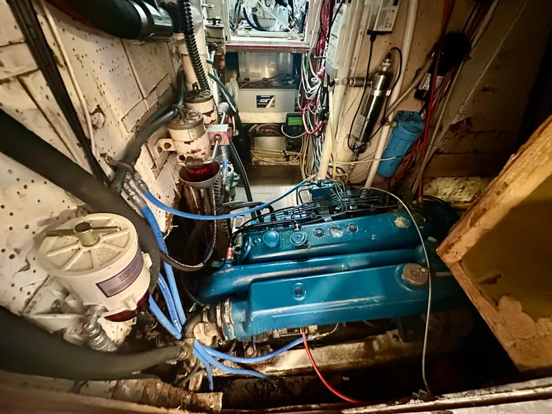 Slide: The Image of Engine room of a 1983 Tayana 55 yacht, featuring a blue engine and various mechanical components. - 44