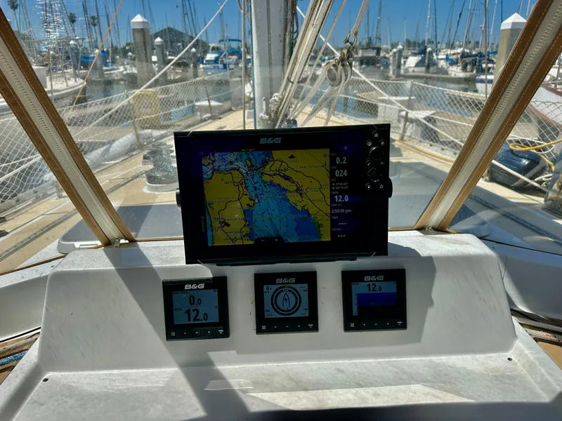 Slide: The Image of Cockpit of 1983 Tayana 55 sailboat with navigation instruments and marina view. - 8